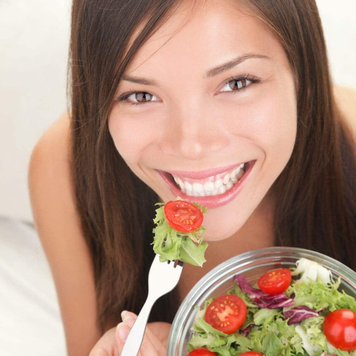 Salad. Portrait of healthy happy woman eating salad. Beautiful smiling Asian Caucasian female model.